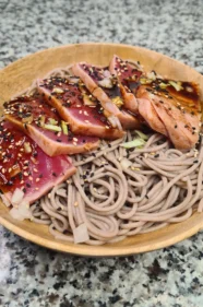 Vista parcial del plato japonés con fideos soba fríos y tataki de atún, con sésamo y cebolleta
